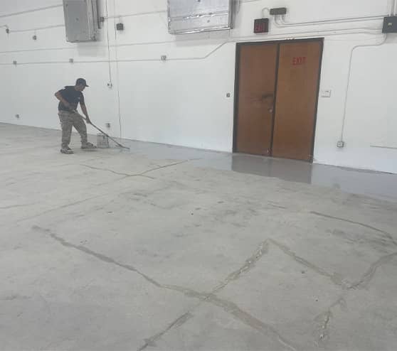 employee in the middle of fixing the concrete on floor