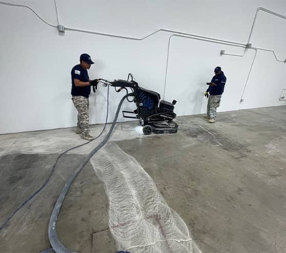 two employees working on fixing the concrete before the new flooring for LLumar Window and Paint Protection Film