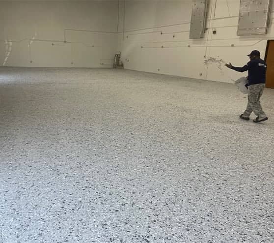 employee working on epoxy flooring for LLumar Window and Paint Protection Film