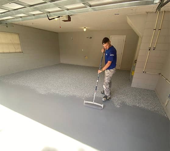 employee laying down epoxy flooring for garage